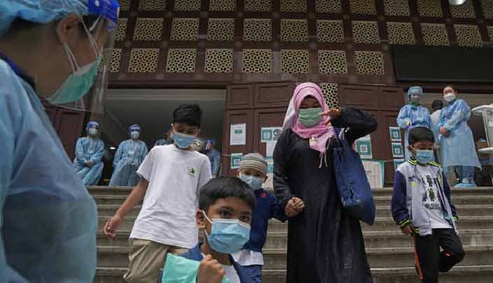 Sebuah keluarga pergi setelah menerima dosis vaksin virus corona COVID-19 Pfizer-BioNTech di pusat vaksinasi komunitas di Kowloon Mosque And Islamic Center di Hong Kong, Sabtu, 19 Maret 2022. [Foto: AP]
